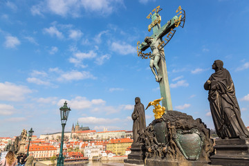 Fototapeta premium View of Charles Bridge statues and crucifix, Prague Castle in Prague, Czech Republic. Nice sunny summer day with blue sky and clouds. Famous landmarks in Europe.