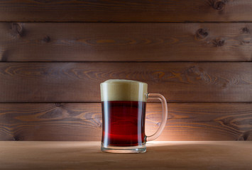 Glass of dark beer on wooden background