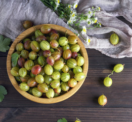 round wooden bowl with green gooseberries