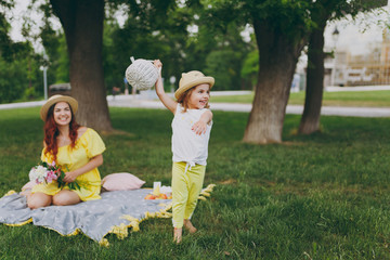 Little cute child baby girl with basket play, have fun and spreading hands with woman in yellow clothes in green park. Mother, little kid daughter. Mother's Day, love family, parenthood, childhood.