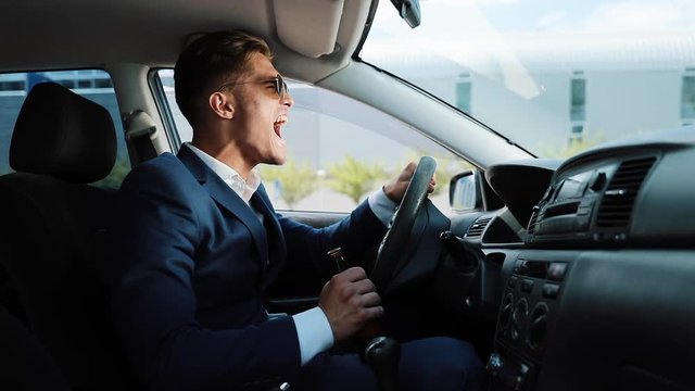 Depressed and very upset young businessman in the car. A man drinks alcohol at the wheel problems in business or personal life
