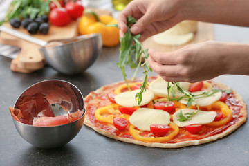 Woman preparing pizza at table in kitchen