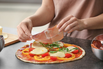 Obraz na płótnie Canvas Woman preparing pizza at table in kitchen
