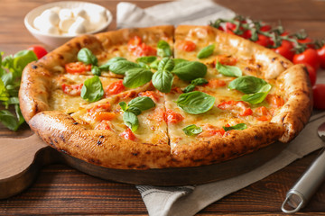 Board with delicious pizza Margherita on wooden table