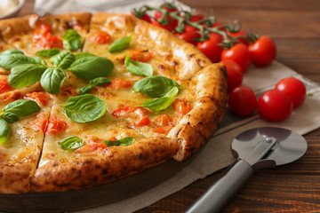 Board with delicious pizza Margherita on wooden table, closeup