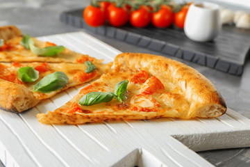 Board with slices of delicious pizza Margherita on table