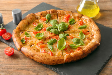 Slate plate with delicious pizza Margherita on wooden table