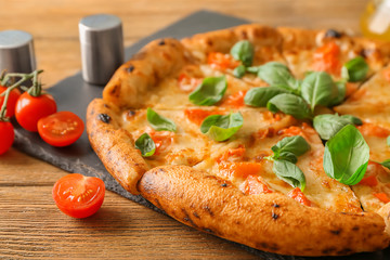 Slate plate with delicious pizza Margherita on wooden table, closeup
