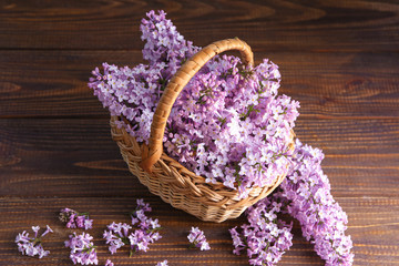 Basket with beautiful blossoming lilac on wooden table