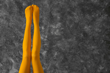 Legs of beautiful young woman in color tights on dark textured background