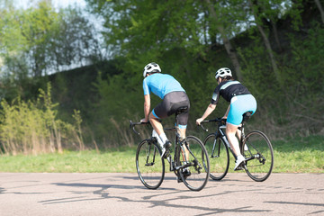 Active male athletes riding bicycles on an open country road