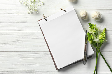 Composition with notebook, candies and beautiful flowers on light background