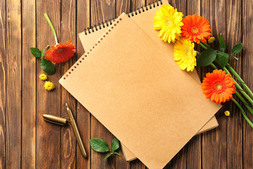 Notebook with beautiful flowers on wooden background