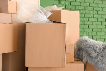 Packed carton boxes near color wall. Moving house concept