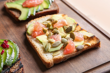 Tasty toasts with avocado on wooden board