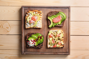 Board with tasty toasts on wooden background