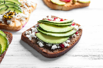 Tasty toasts with avocado on wooden background