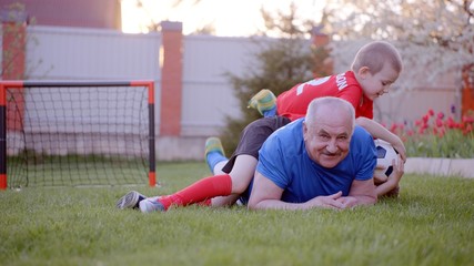 Fototapeta na wymiar Happy old man with his grandsons playing football