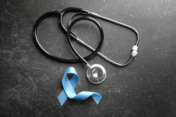 Blue ribbon and stethoscope on dark background. Prostate cancer concept