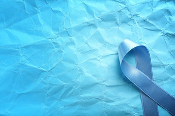 Blue ribbon on color creased paper. Prostate cancer concept