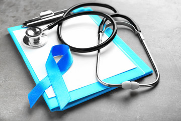 Blue ribbon, stethoscope and clipboard on grey background. Prostate cancer concept