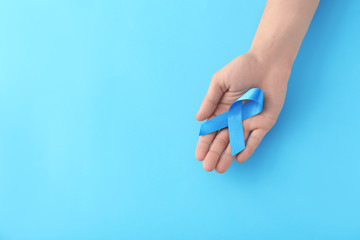 Fototapeta na wymiar Male hand holding blue ribbon on color background. Prostate cancer concept