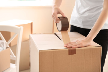 Woman packing carton box indoors. Moving house concept