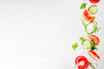 Creative background, layout, concept of fresh healthy diet of salad, fresh raw  vegetables tomatoes parsley onions cucumbers greens, simple pattern on white background