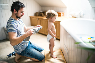 Father with a toddler child at home, getting ready for a bath.