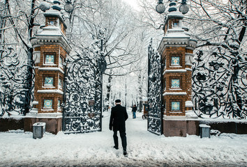 Open carved cast-iron gates and famous lattice /fence of Mikhailovsky Garden in winter frosty day, people are walking in park, St. Petersburg, Russia