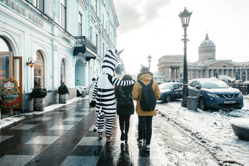 Happy tourists walk along Petersburg paved streets (Griboedova Canal and Nevsky Prospekt) next to...