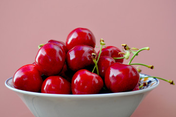 cherries in a bowl wiyh pink background