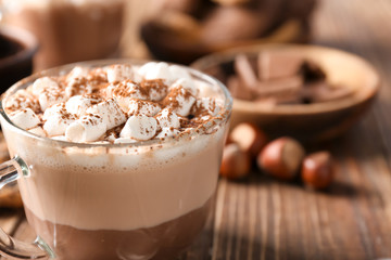 Cup with hot cocoa drink and marshmallows on wooden table, closeup