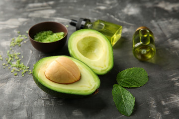Avocado with sea salt and oil for homemade cosmetics on grey background