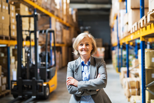 Senior woman warehouse manager or supervisor , arms crossed.