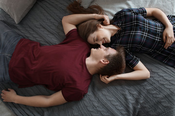 Happy young couple resting on bed at home