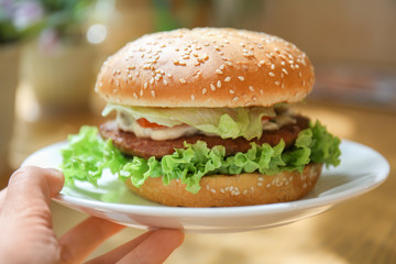 Woman holding plate with tasty burger, closeup