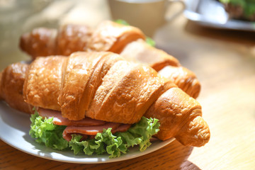 Plate with tasty croissant on table