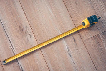 Construction tape measure on a wooden floor