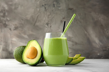 Ripe avocados and glass of tasty smoothie on table