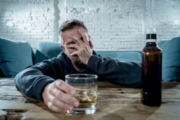 young drunk man depressed and sad drinking whiskey at home - obrazy, fototapety, plakaty