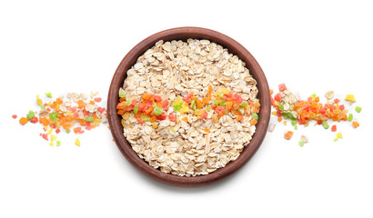 Bowl with oatmeal flakes and candied fruits on white background