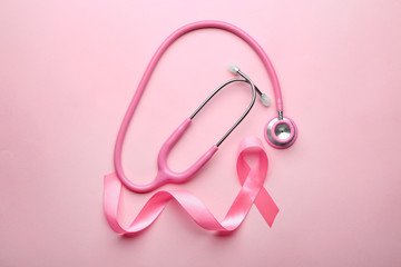 Obraz na płótnie Canvas Pink ribbon and stethoscope on color background. Breast cancer awareness concept
