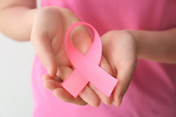 Woman holding pink ribbon, closeup. Breast cancer awareness concept
