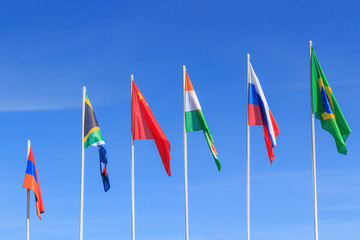 Flags of BRICS countries on a blue sky background