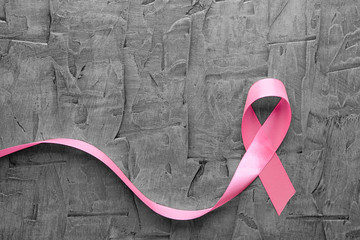 Pink ribbon on grey textured background. Breast cancer concept