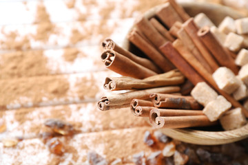Bowl with cinnamon sticks and sugar on wooden background, closeup