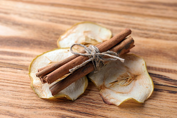 Cinnamon sticks and dried apple slices on wooden background