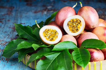 Fresh passion fruit with original leaves on blue wooden background