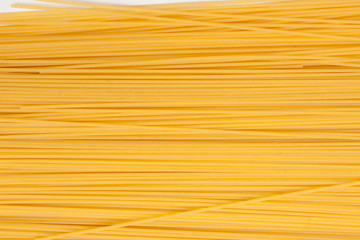 Yellow long spaghetti on black background. Thin pasta arranged in rows. Yellow italian pasta. Long spaghetti. Raw spaghetti wallpaper. Thin spaghetti. Food background concept. 

